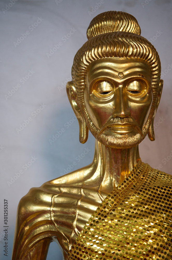 Ancient golden statue of a skinny meditating Buddha with ribs and veins showing while he fasted during his search for enlightenment