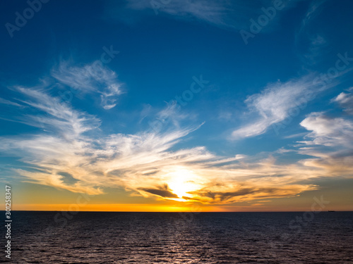 Scenic sunrise at open sea with clouds and blue sky.