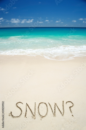 Tropical vacation escape from cold weather featuring Snow? message in the sand next to bright blue seas on the beach