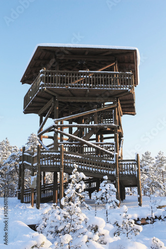 Wooden observation tower in the forest with a snowy roof. Winter landscape.