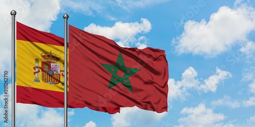 Canvas Print Spain and Morocco flag waving in the wind against white cloudy blue sky together