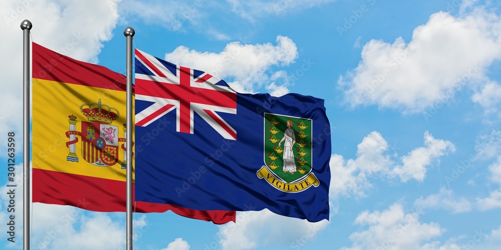 Spain and British Virgin Islands flag waving in the wind against white cloudy blue sky together. Diplomacy concept, international relations.