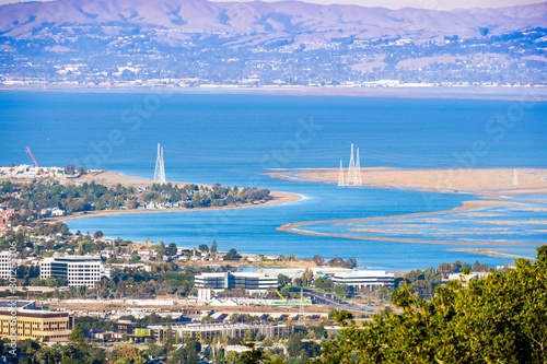 Aerial view of wetlands in the San Francisco Bay Area; Office buildings, residential areas and electricity towers visible on the shoreline; San Carlos, California photo