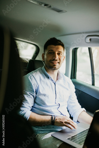 Portrait of man working on laptop in car on backseat © F8  \ Suport Ukraine