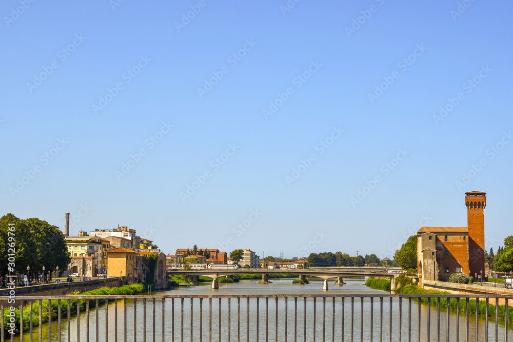 Scenic view of the Arno river from Solferino Bridge with Cittadella Bridge and the Guelfa Tower (1407) in the famous Tuscan town of Pisa in a sunny summer day, Tuscany, Italy
