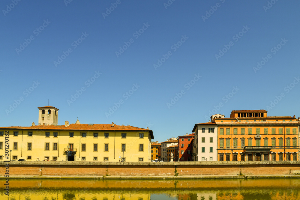 Scenic view of Lungarno Antonio Pacinotti riverside with the Torre de Cantone tower and the Royal Palace (Palazzo Reale) in a sunny summer day, Pisa, Tuscany, Italy