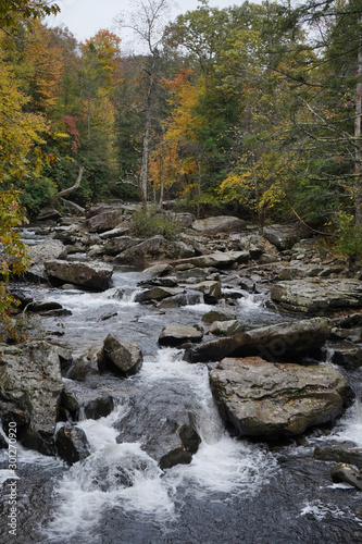 Beautiful river view at the Babcock State Park in West Virginia. Water flowing over large rocks during the autumn season.