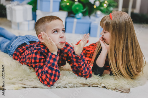 Cute little spend pleasant time together, communicating on the carpet near Christmas tree. photo