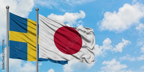 Photography Sweden and Japan flag waving in the wind against white cloudy blue sky together
