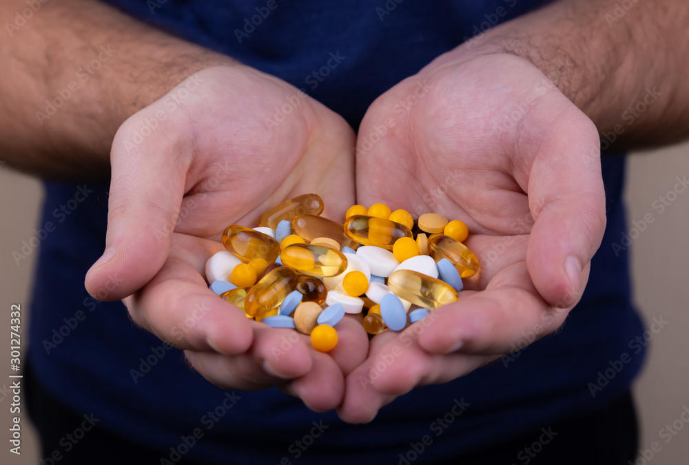 A pile of multi-colored pills in a male hand. A man holds pills in his hand. The concept of medicine, illness, health A pile of multi-colored pills in a male hand. A man holds pills in his hand. The concept of medicine, illness, health