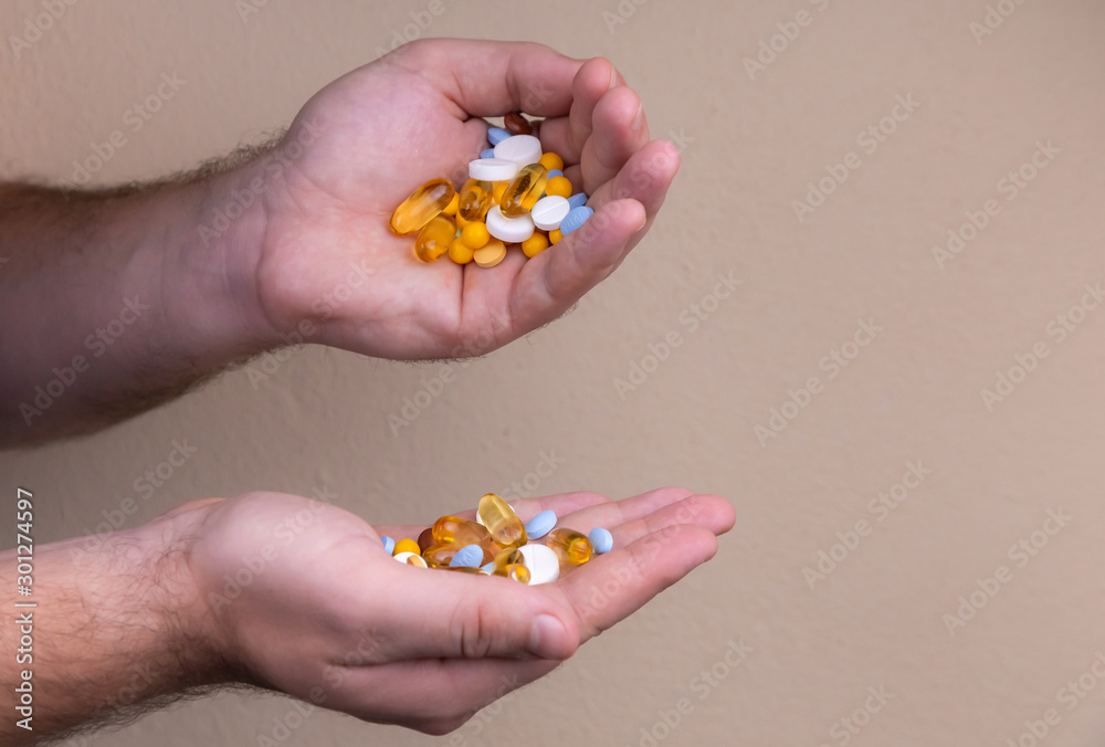 A pile of multi-colored pills in a male hand. A man holds pills in his hand. The concept of medicine, illness, health A pile of multi-colored pills in a male hand. A man holds pills in his hand. The concept of medicine, illness, health