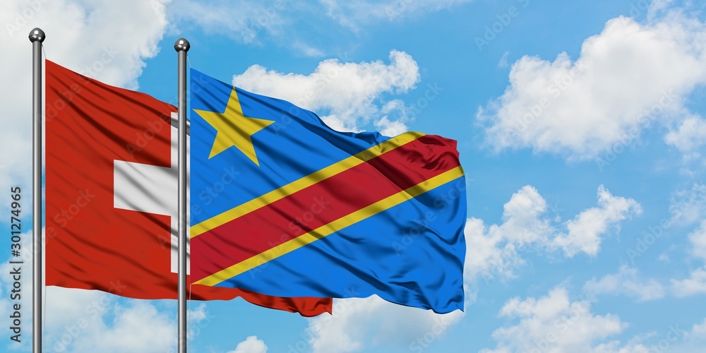 Switzerland and Congo flag waving in the wind against white cloudy blue sky together. Diplomacy concept, international relations.