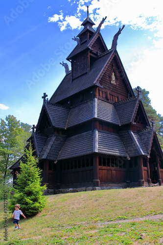 Little two years old boy running and playing in front of the Gol Church,  a stave church originally built in Gol city, but now located in the Norwegian Museum of Cultural History at Bygdoy in Oslo, No photo