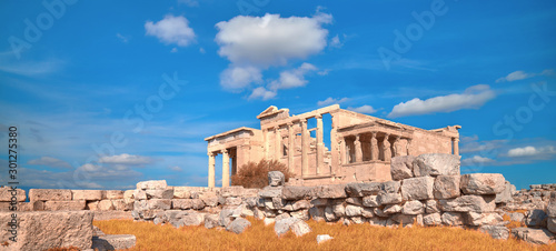 Panoramic image of Erechtheion temple Acropolis, Athens, Greece, with famous Caryatides in Autumn with orange grass and blue sky with clouds photo