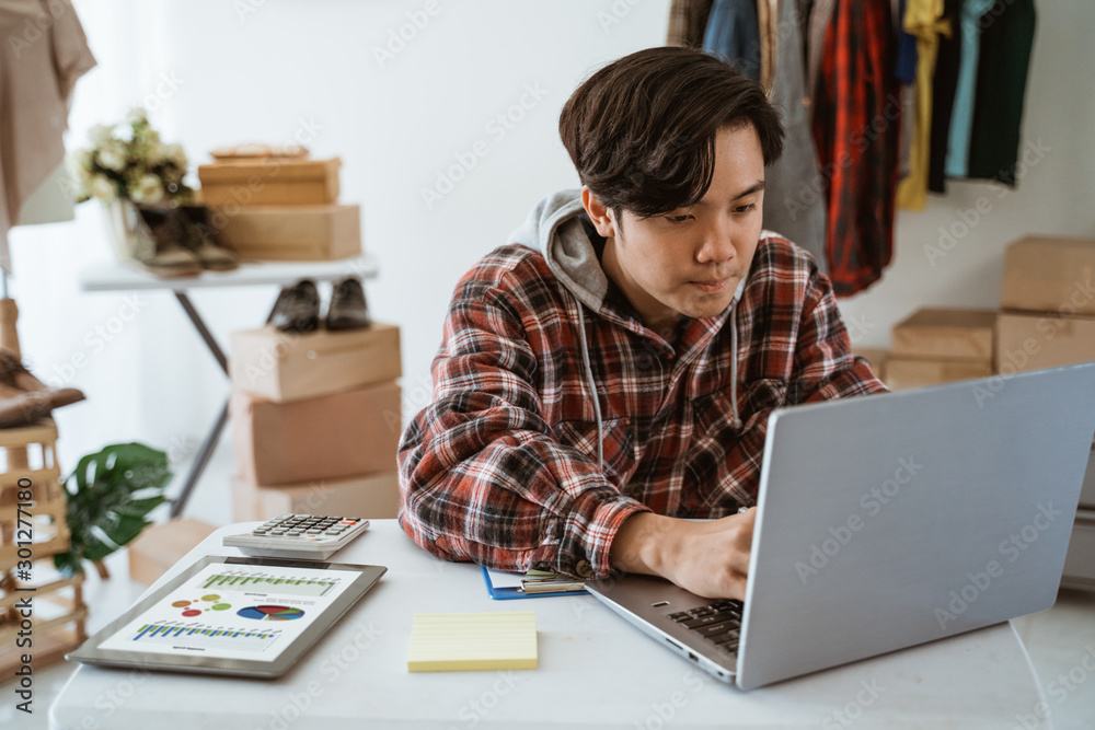 young man taking note of orders from customers. Dropshipping business owner working in his office young man taking note of orders from customers. Dropshipping business owner working in his office