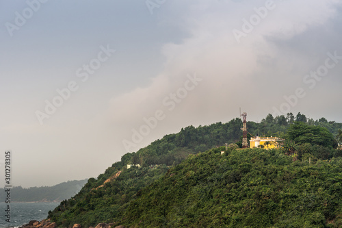 Da Nang  Vietnam - March 10  2019  Tien Sa Port in Da Nang Bay. Yellow building and tall antenna set up in green hills under evening cloudscape above the harbor.