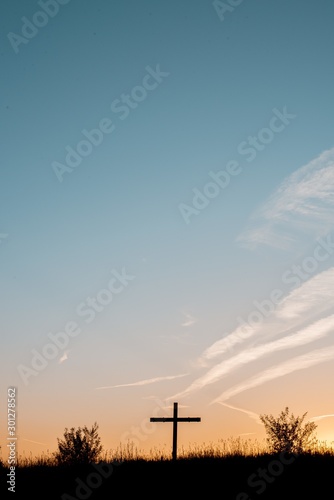 Tela Silhouette of a wooden cross on a grassy hill with a sky