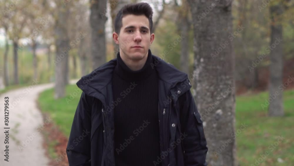 A young man walks through the autumn park . A young man walks through the autumn park .