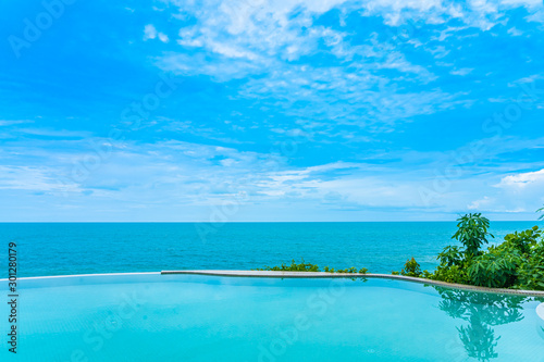 Beautiful outdoor infinity swimming pool in hotel resort with sea ocean view and white cloud blue sky