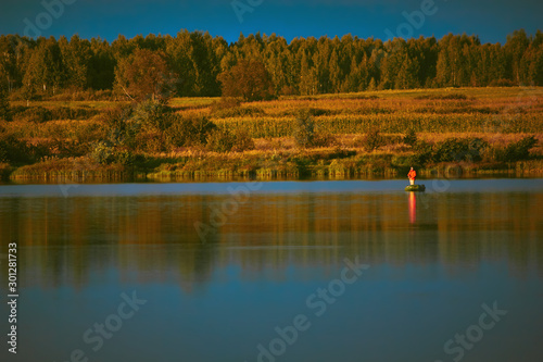 Fisherman on a boat in the autumn on the lake