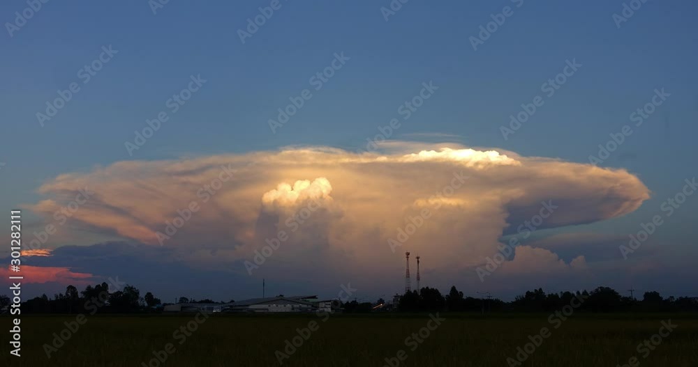 Big cloud storm over rice field and village. twilight sunset and colorful clouds - sunlight with dramatic cloud and moon.Time lapse day to night. Big cloud storm over rice field and village. twilight sunset and colorful clouds - sunlight with dramatic cloud and moon.Time lapse day to night.