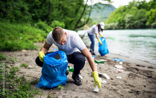 Group of young volunteers cleaning river shore