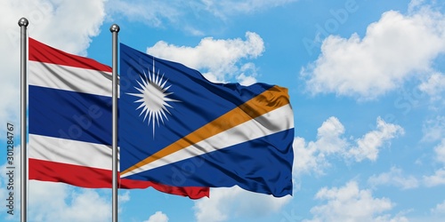 Thailand and Marshall Islands flag waving in the wind against white cloudy blue sky together. Diplomacy concept, international relations.
