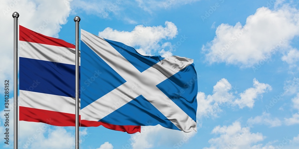 Thailand and Scotland flag waving in the wind against white cloudy blue sky together. Diplomacy concept, international relations.