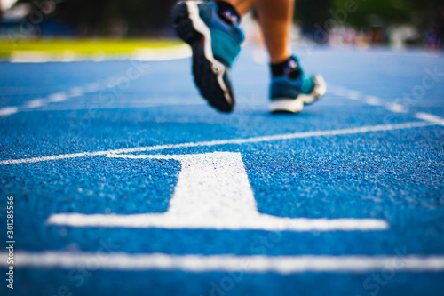 Number one on the start of a running track .Blue treadmill with different numbers and white lines.Selective focus on Number. Blured background. Close up