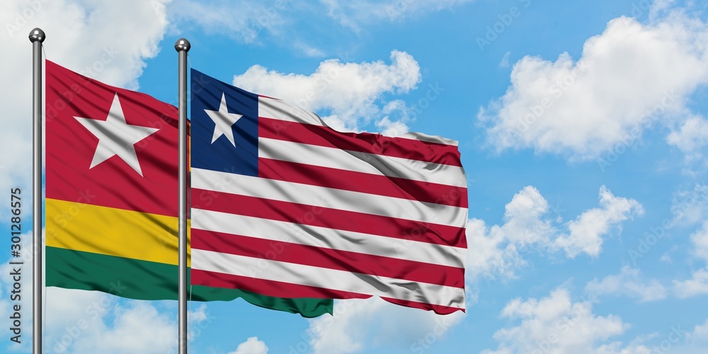 Togo and Liberia flag waving in the wind against white cloudy blue sky together. Diplomacy concept, international relations. Togo and Liberia flag waving in the wind against white cloudy blue sky together. Diplomacy concept, international relations.