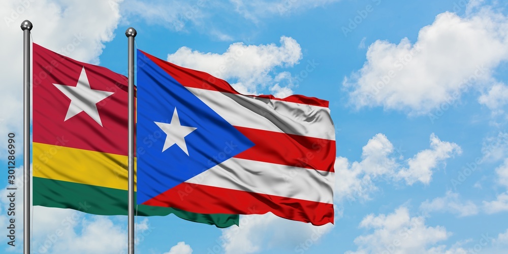 Togo and Puerto Rico flag waving in the wind against white cloudy blue sky together. Diplomacy concept, international relations.