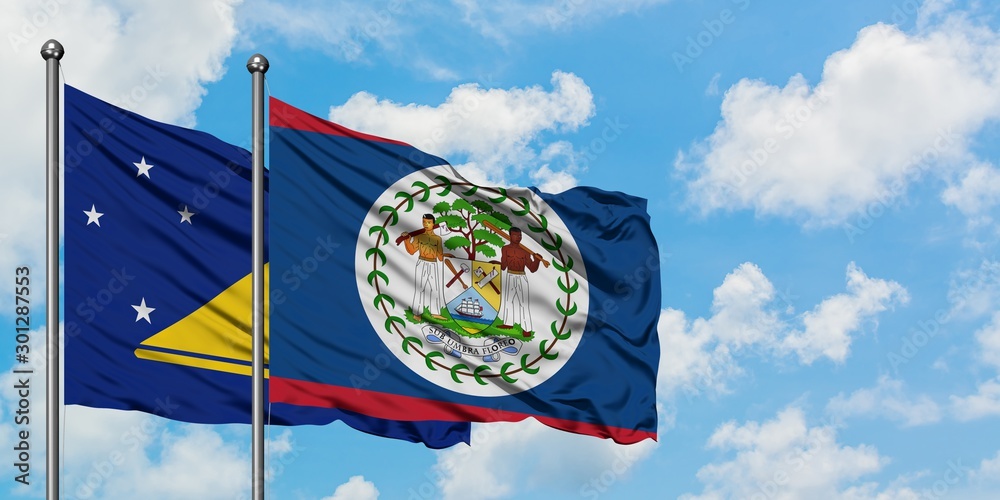 Tokelau and Belize flag waving in the wind against white cloudy blue sky together. Diplomacy concept, international relations. Tokelau and Belize flag waving in the wind against white cloudy blue sky together. Diplomacy concept, international relations.