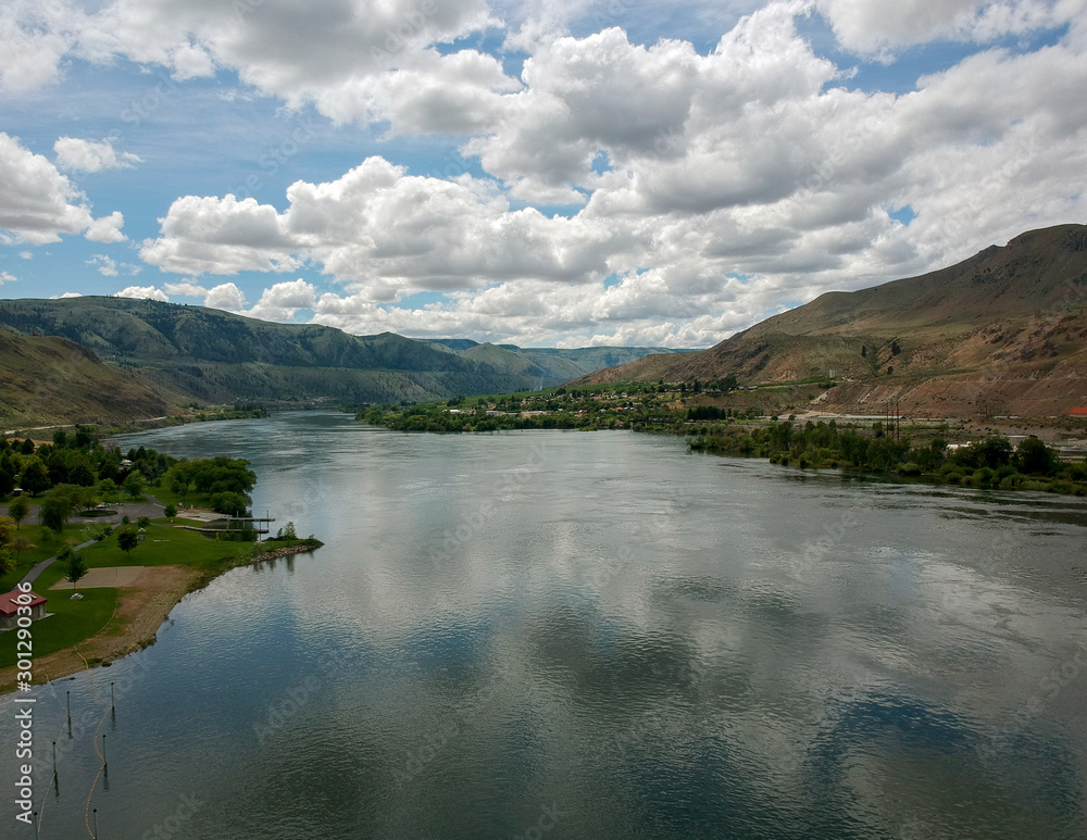 Remarkable Aerial Photography of Beebe Bridge Park with a clear blue sky and bright cumulus clouds in a craggy mountain setting with the Columbia River outside Chelan Washington.
