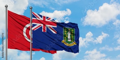 Tunisia and British Virgin Islands flag waving in the wind against white cloudy blue sky together. Diplomacy concept, international relations.