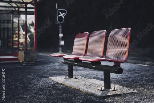 Three red seats in the bus station of an urban area