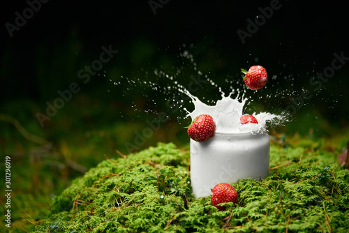 Strawberries falling into milk