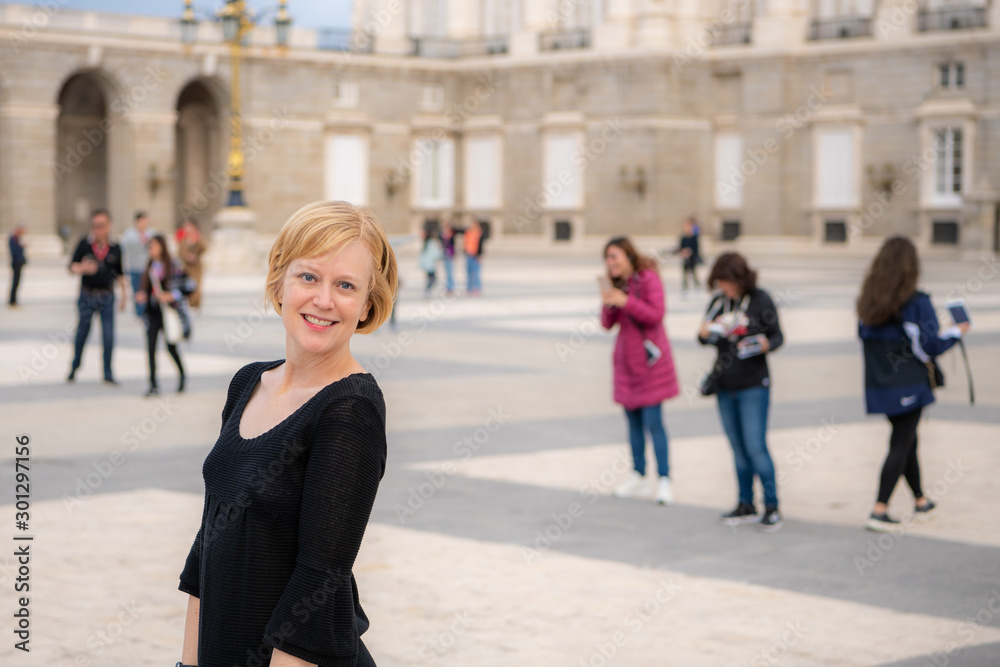 A woman enjoys traveling in Spain and poses for photos in the beautiful Plaza de la Armería in front of the Royal Palace. Photography is permitted outside the palace.