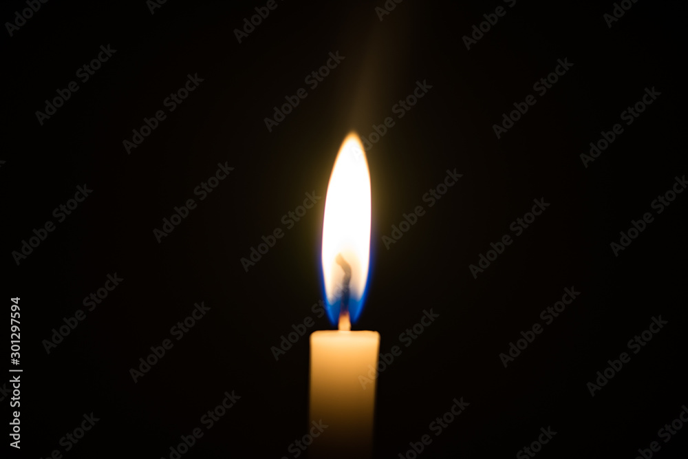 One candle light illuminated in a black background. One candle light illuminated in a black background.