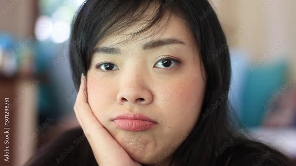 Young Asian woman sighing expressing disappointment with pursed lips with blurred background. Young Asian woman sighing expressing disappointment with pursed lips with blurred background.