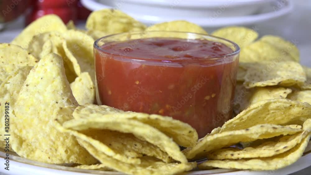 Pouring gourmet salsa into a bowl surrounded by tortilla chips