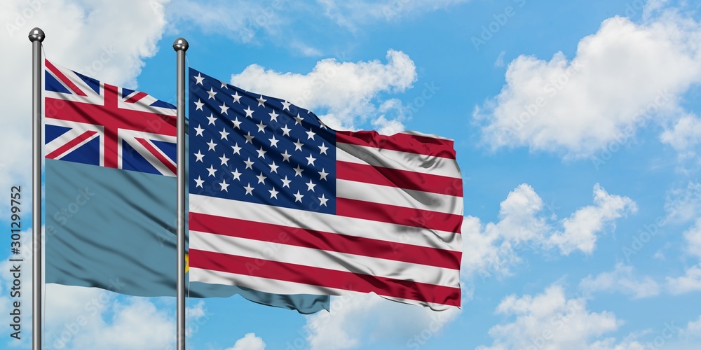 Tuvalu and United States flag waving in the wind against white cloudy blue sky together. Diplomacy concept, international relations. Tuvalu and United States flag waving in the wind against white cloudy blue sky together. Diplomacy concept, international relations.