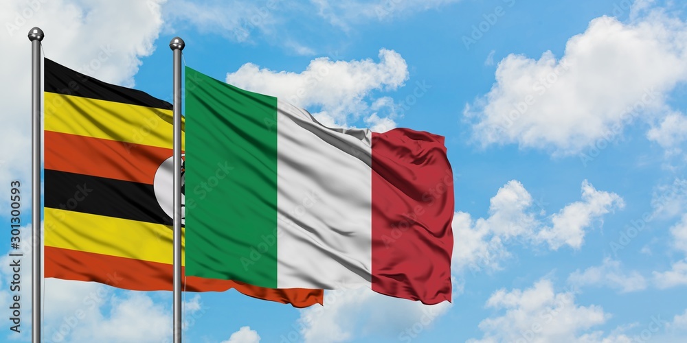 Uganda and Italy flag waving in the wind against white cloudy blue sky together. Diplomacy concept, international relations.