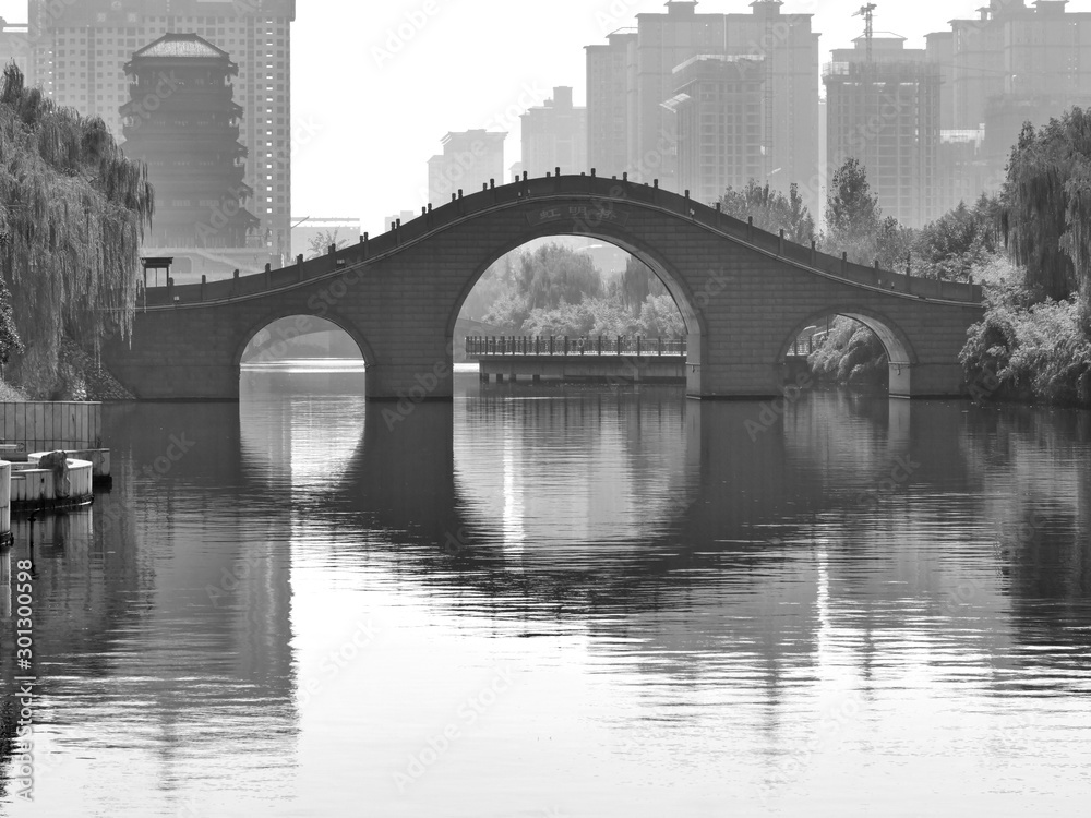 Oriental bridge reflecting in the river with the modern city in the background