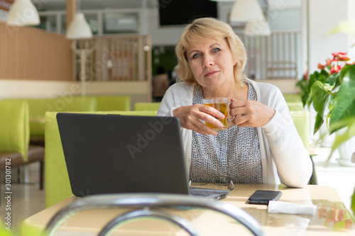 A woman with a laptop looks at a document in a cafe  office