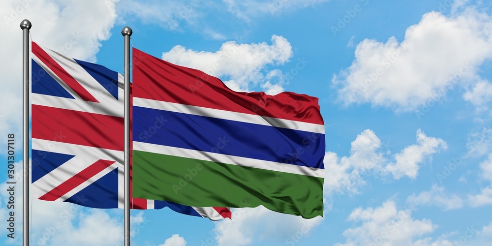 United Kingdom and Gambia flag waving in the wind against white cloudy blue sky together. Diplomacy concept, international relations.
