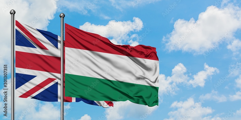 United Kingdom and Hungary flag waving in the wind against white cloudy blue sky together. Diplomacy concept, international relations.
