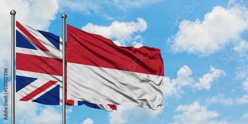 United Kingdom and Indonesia flag waving in the wind against white cloudy blue sky together. Diplomacy concept, international relations.
