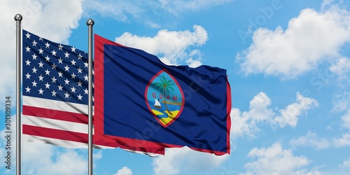 United States and Guam flag waving in the wind against white cloudy blue sky together. Diplomacy concept, international relations.
