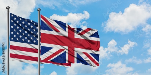 United States and United Kingdom flag waving in the wind against white cloudy blue sky together. Diplomacy concept, international relations.