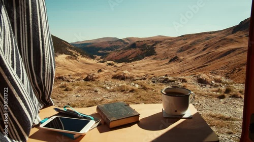 Work and Travel Van Life with hot coffee plus notebook plus cellphone in front of quiet and deserted mountain valley panorama at Transalpina Road in Romania photo